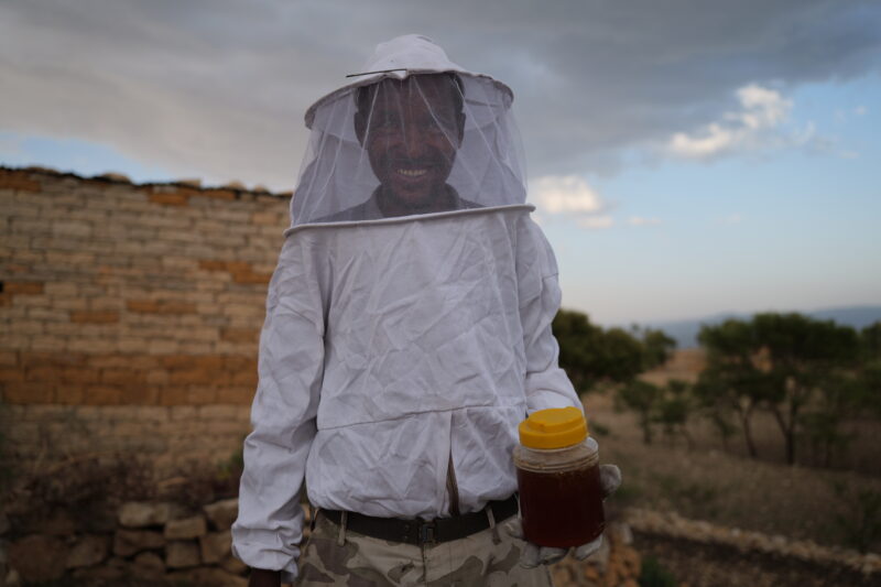 A local beekeeper proudly holding a pot of freshly harvested honey